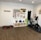 A fitness room featuring a variety of workout equipment neatly organized. The wall has a pegboard displaying exercise bands, foam rollers, and ropes. Below the board, there are kettlebells and dumbbells on shelves. An exercise bike is positioned to the right, with a step platform on the left.