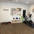 A fitness room featuring a variety of workout equipment neatly organized. The wall has a pegboard displaying exercise bands, foam rollers, and ropes. Below the board, there are kettlebells and dumbbells on shelves. An exercise bike is positioned to the right, with a step platform on the left.